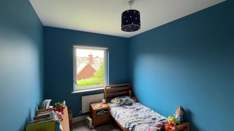 Child’s bedroom painted in a rich petrol blue with a white ceiling