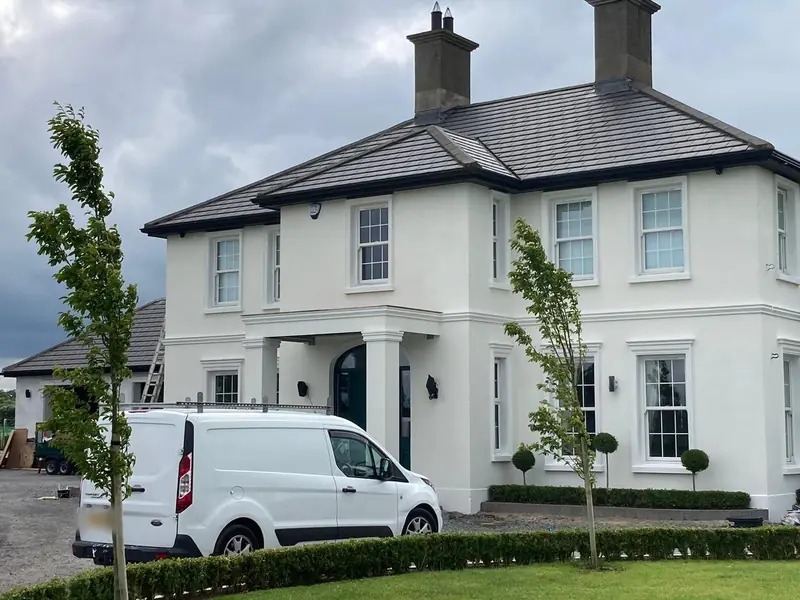 After: the same house painted white, with crisp white window surrounds and a white van on the drive