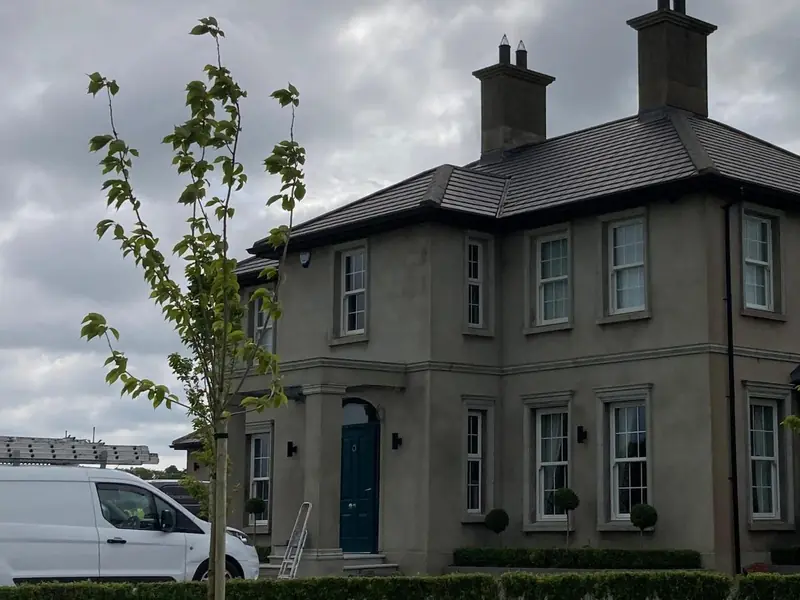 Before: a two-storey house with plain grey render, a teal front door and a ladder at the porch